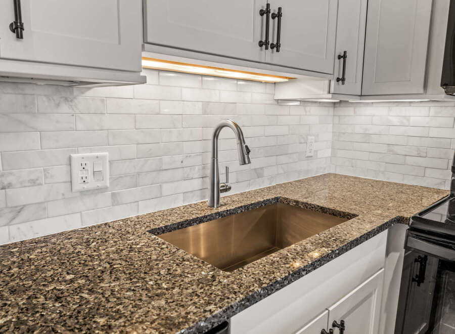 This stunning kitchen boasts a modern design with sleek white cabinetry and a beautiful granite countertop.