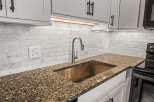 This stunning kitchen boasts a modern design with sleek white cabinetry and a beautiful granite countertop.