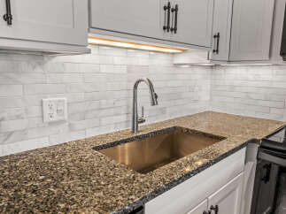 This stunning kitchen boasts a modern design with sleek white cabinetry and a beautiful granite countertop.
