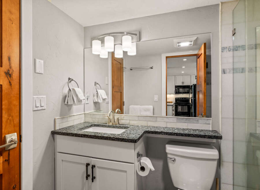 This stunning bathroom features a modern vanity with a granite countertop and a sleek, undermount sink.