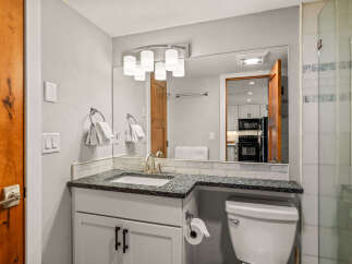 This stunning bathroom features a modern vanity with a granite countertop and a sleek, undermount sink.