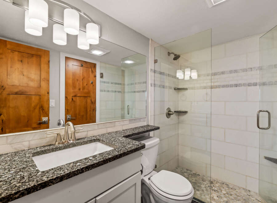 Step into this beautifully designed bathroom, featuring a sleek glass shower and a stylish vanity with a granite countertop.