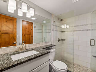Step into this beautifully designed bathroom, featuring a sleek glass shower and a stylish vanity with a granite countertop.