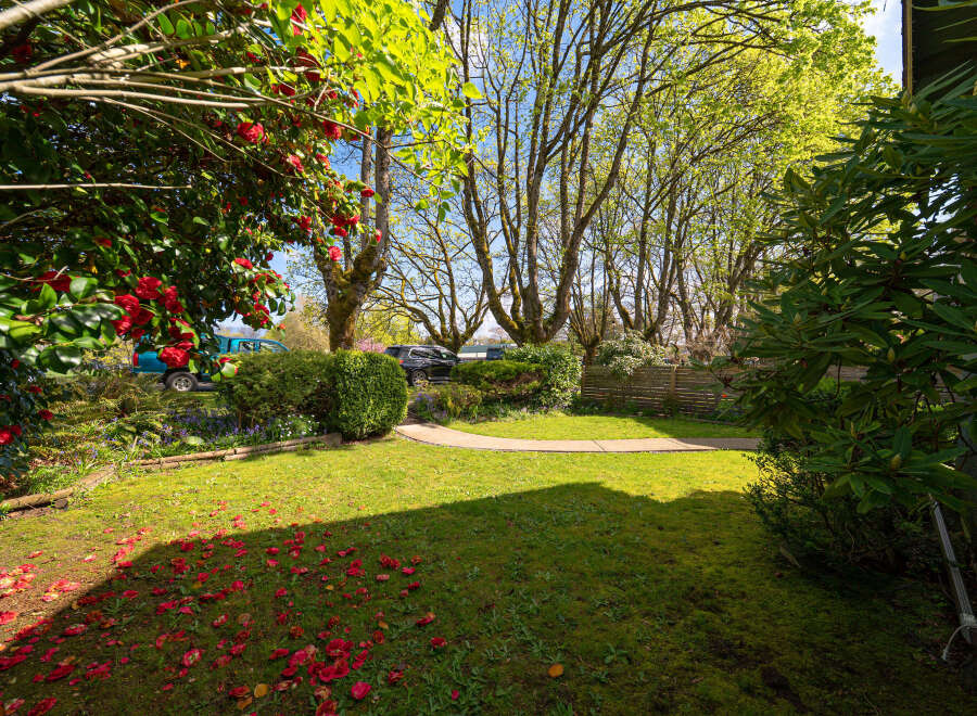 Discover the charm of this beautiful property, featuring a lush green lawn and vibrant red flowers.