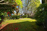 Discover the charm of this beautiful property, featuring a lush green lawn and vibrant red flowers.