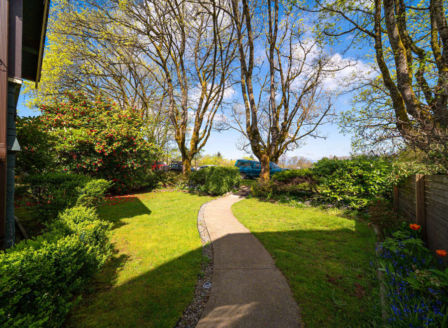 Discover the charm of this beautifully landscaped property, featuring a winding pathway that leads through lush greenery.