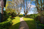 Discover the charm of this beautifully landscaped property, featuring a winding pathway that leads through lush greenery.