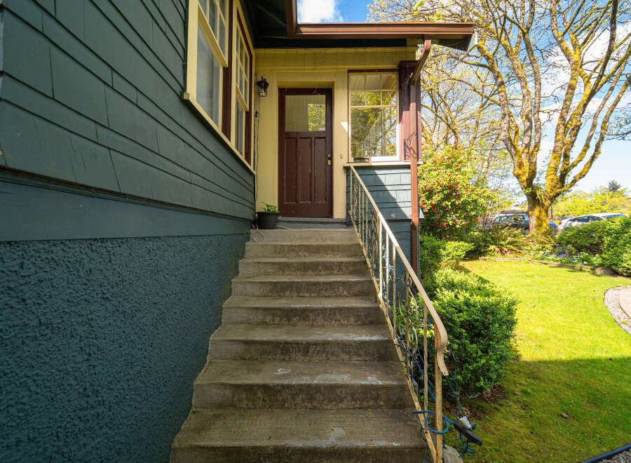 This charming home features a welcoming entrance with a covered porch and a set of concrete steps.