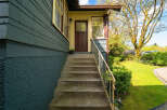 This charming home features a welcoming entrance with a covered porch and a set of concrete steps.