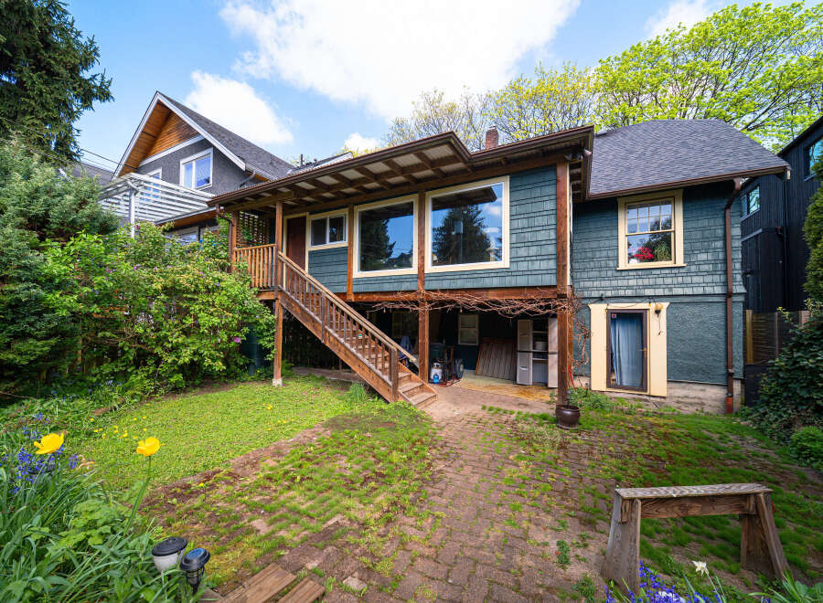 This charming two-story home boasts a unique design with a covered porch and a welcoming wooden staircase.