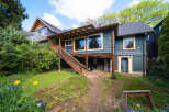 This charming two-story home boasts a unique design with a covered porch and a welcoming wooden staircase.
