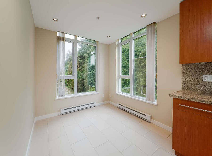 This bright and airy space features large windows that flood the room with natural light, offering stunning views of the lush greenery outside.