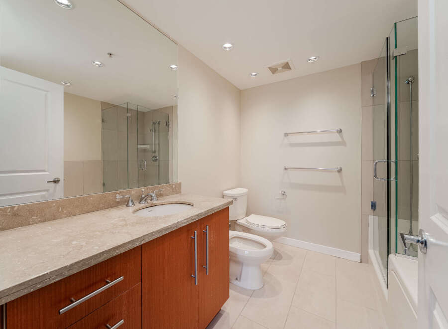 Step into this modern bathroom, featuring a sleek vanity with a stone countertop and ample storage.