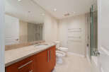 Step into this modern bathroom, featuring a sleek vanity with a stone countertop and ample storage.