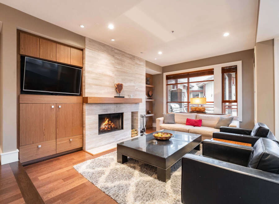 Experience luxury living in this stunning property, featuring a cozy living room with a fireplace and a modern entertainment center.