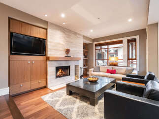 Experience luxury living in this stunning property, featuring a cozy living room with a fireplace and a modern entertainment center.