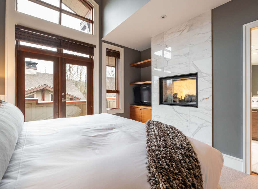 Experience luxury in this stunning bedroom featuring a modern fireplace and elegant marble accents.