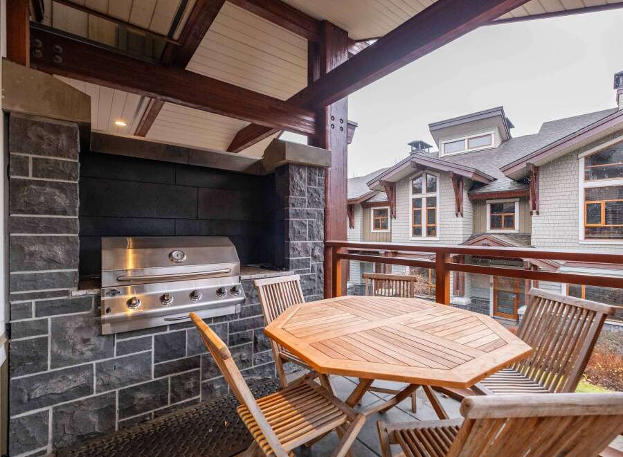 Enjoy outdoor living at its finest with this stunning property featuring a built-in grill and a cozy dining area.