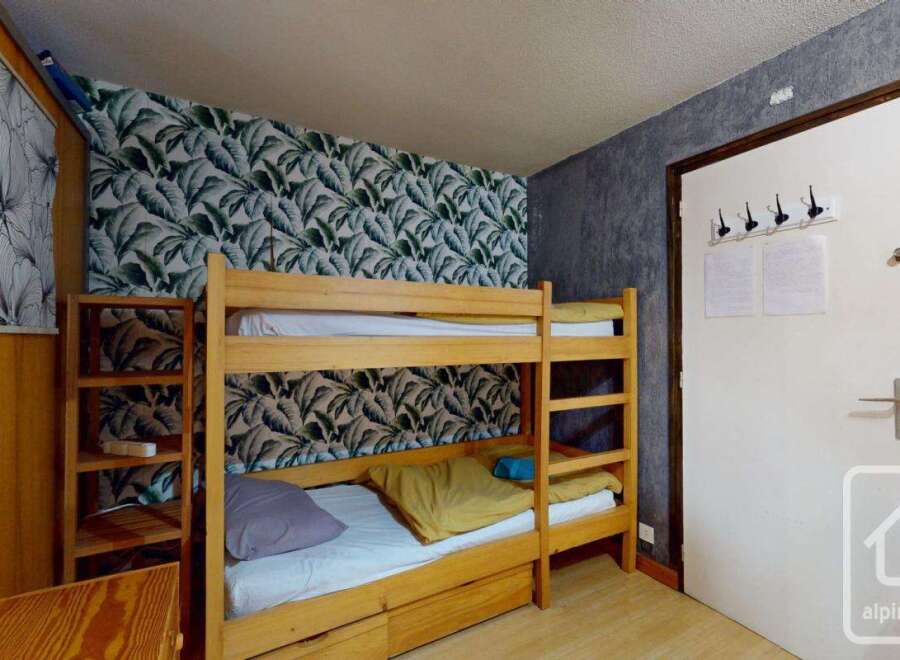 Discover this cozy bedroom featuring a charming bunk bed, perfect for accommodating guests or family.