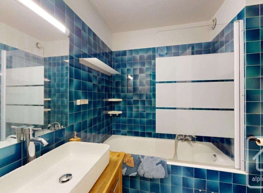 Step into this stylish bathroom featuring stunning blue tiles that create a serene and inviting atmosphere.