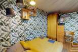 This cozy bedroom features a vibrant tropical leaf wallpaper, creating a refreshing and inviting atmosphere.