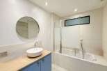This modern bathroom boasts a sleek design with a round mirror, a stylish sink, and a bathtub.