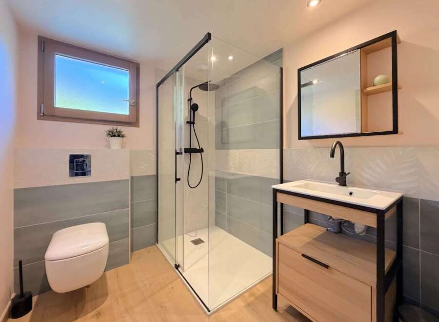Step into this modern bathroom, featuring a sleek glass shower enclosure and stylish vanity.