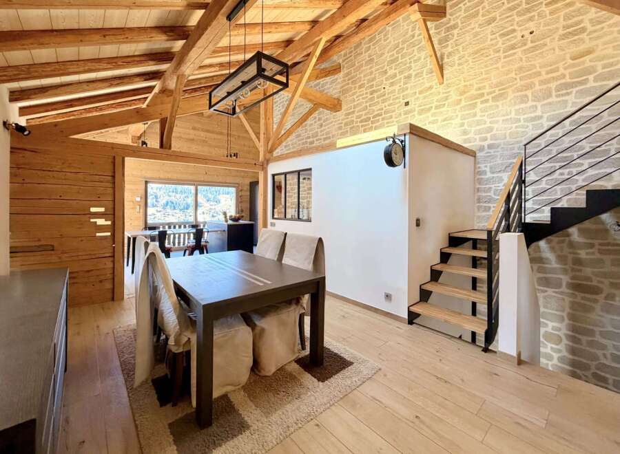 This stunning property boasts a warm and inviting interior with exposed wooden beams and a stone accent wall.