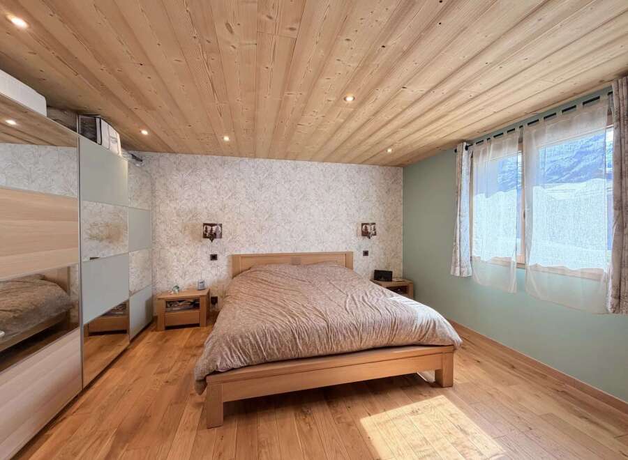 This cozy bedroom features a warm wooden ceiling and flooring, creating a rustic and inviting atmosphere.