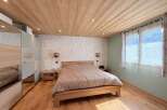 This cozy bedroom features a warm wooden ceiling and flooring, creating a rustic and inviting atmosphere.