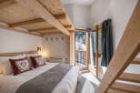 This charming bedroom features a cozy bed with decorative pillows and a wooden ceiling, creating a warm and inviting atmosphere.