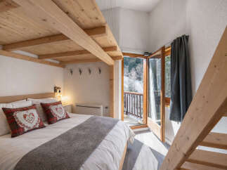 This charming bedroom features a cozy bed with decorative pillows and a wooden ceiling, creating a warm and inviting atmosphere.