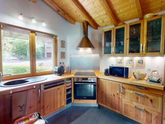 This charming kitchen boasts a warm and inviting atmosphere with its wooden cabinets and exposed beam ceiling.