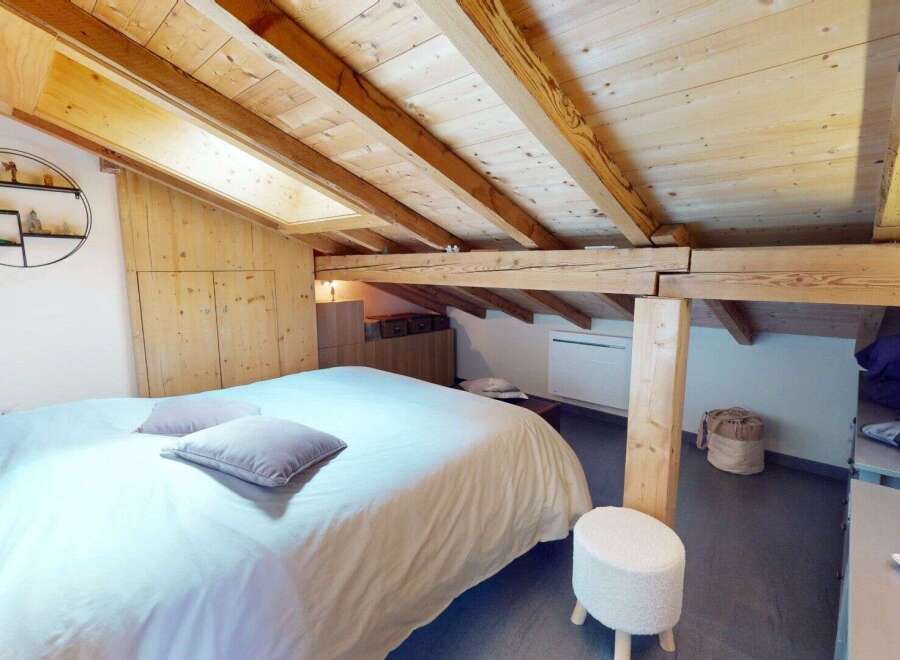 Discover the charm of this cozy bedroom featuring a unique wooden ceiling and a comfortable bed.