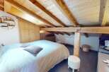 Discover the charm of this cozy bedroom featuring a unique wooden ceiling and a comfortable bed.