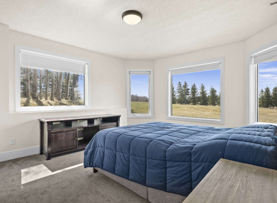 This inviting bedroom offers a serene retreat with its ample natural light and picturesque views.