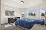 This inviting bedroom offers a serene retreat with its ample natural light and picturesque views.