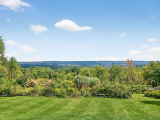 Enjoy breathtaking views from this stunning property! This expansive estate features lush green lawns, mature trees, and a serene natural landscape.
