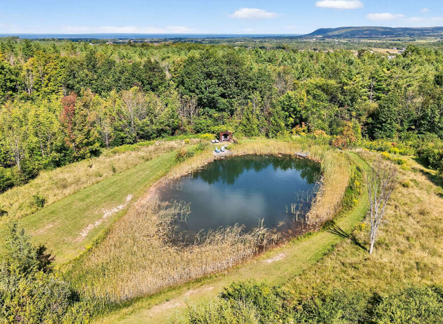 Discover a serene retreat with this stunning property featuring a picturesque pond surrounded by lush greenery.