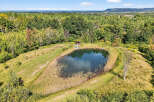 Discover a serene retreat with this stunning property featuring a picturesque pond surrounded by lush greenery.