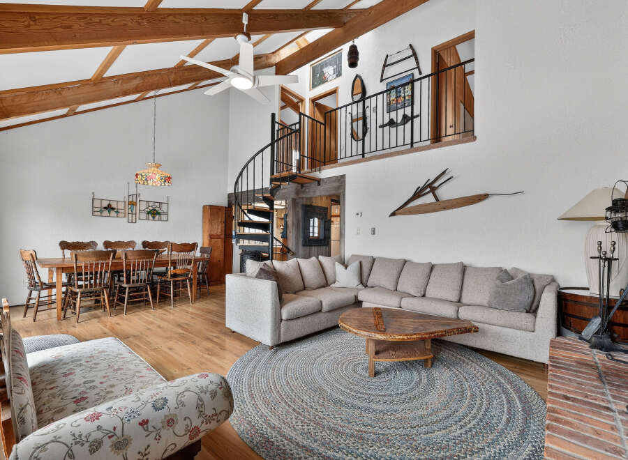 This stunning property boasts a spacious living area with high ceilings and exposed wooden beams, creating a warm and inviting atmosphere.