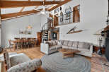 This stunning property boasts a spacious living area with high ceilings and exposed wooden beams, creating a warm and inviting atmosphere.