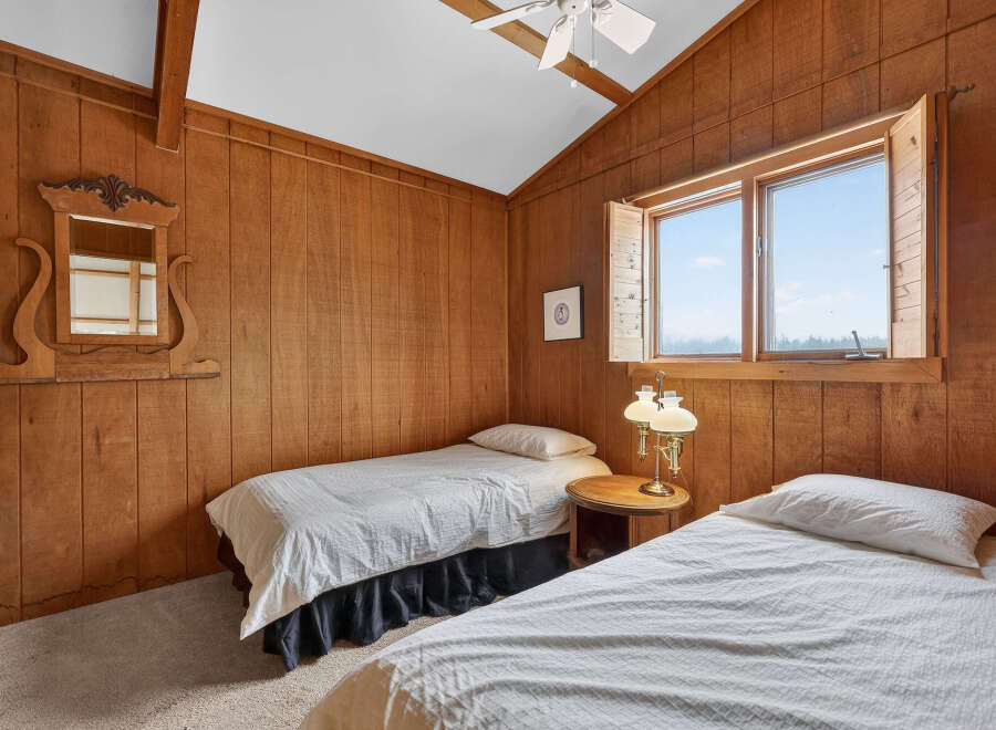 This cozy bedroom features warm wood paneling and two twin beds, perfect for a guest room or vacation rental.