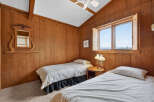This cozy bedroom features warm wood paneling and two twin beds, perfect for a guest room or vacation rental.