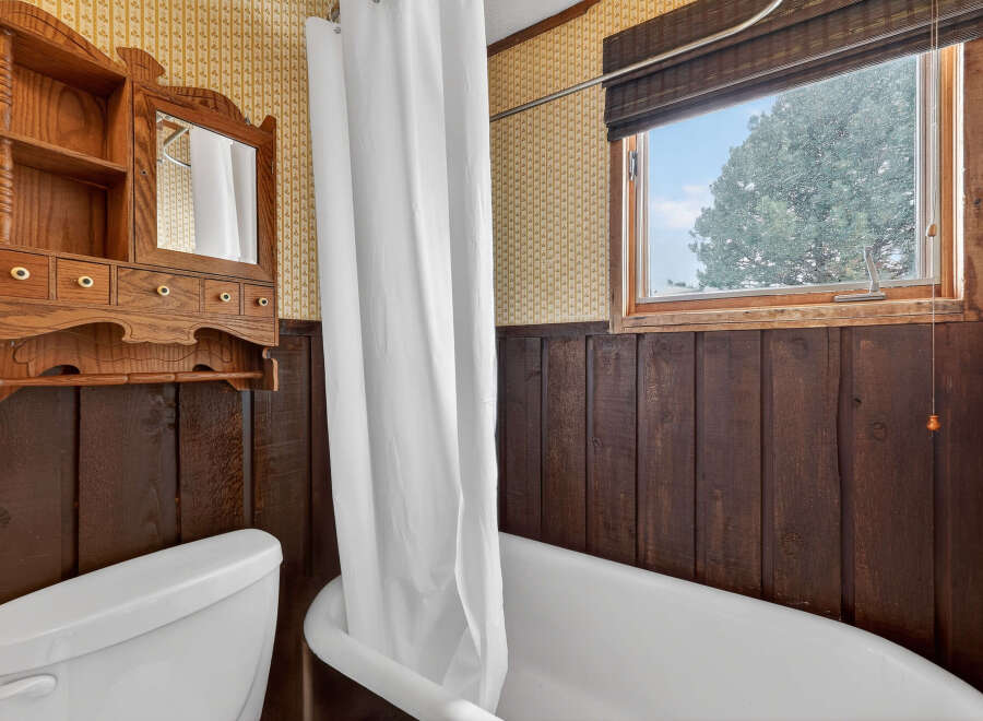 Step into this charming bathroom featuring a classic clawfoot tub and a vintage wooden vanity.
