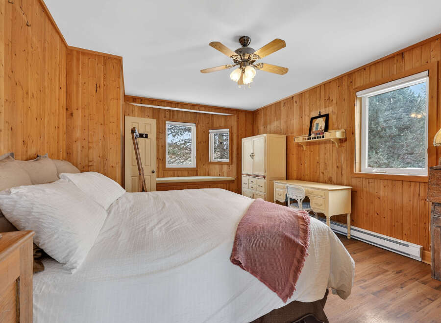 Step into this cozy bedroom featuring warm wood paneling and a comfortable bed.