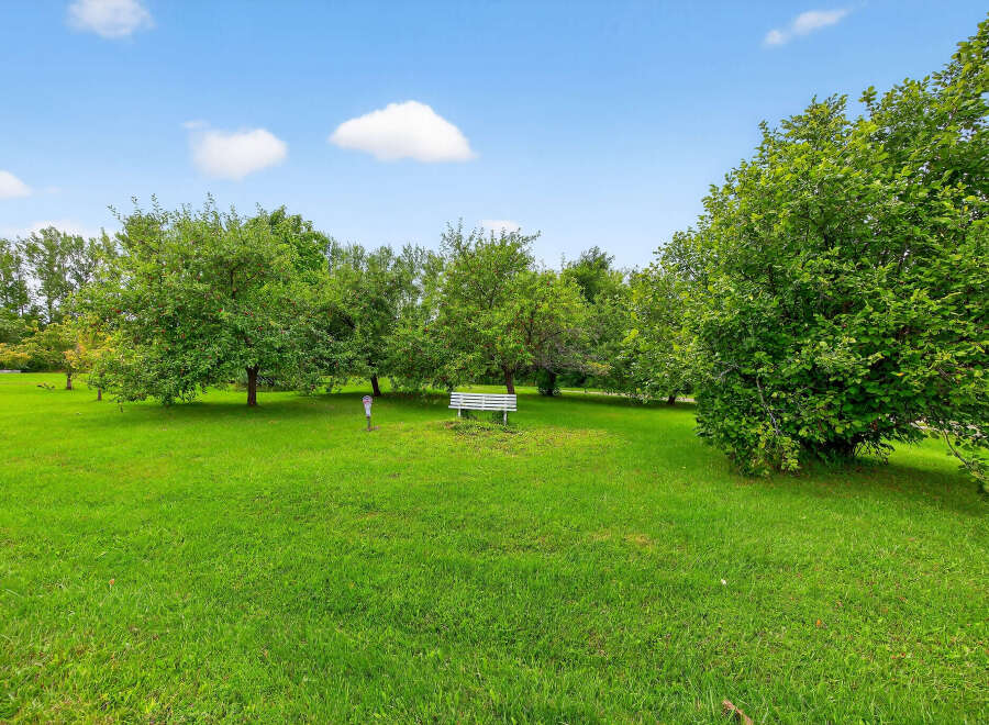 Discover the tranquility of this beautiful property, featuring lush green lawns and mature trees.