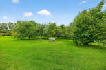 Discover the tranquility of this beautiful property, featuring lush green lawns and mature trees.