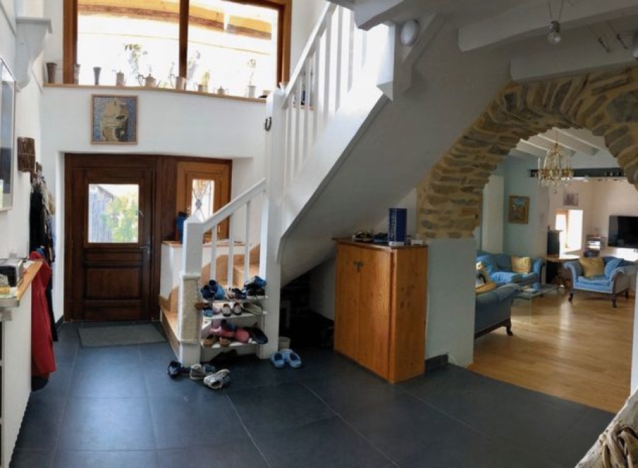 This charming home features a spacious entryway with ample storage, a stunning stone archway leading to the living area, and a beautiful wooden staircase.