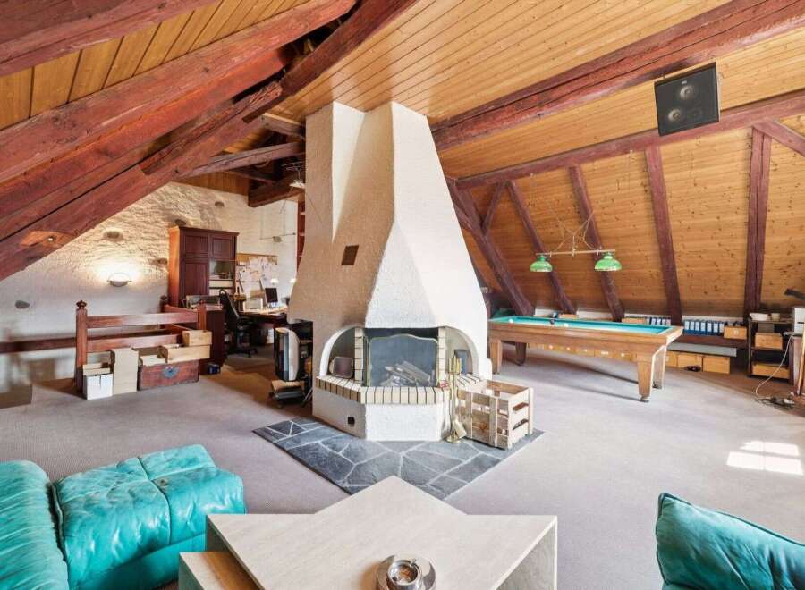 This stunning property boasts a unique and spacious interior with exposed wooden beams and a cozy fireplace.